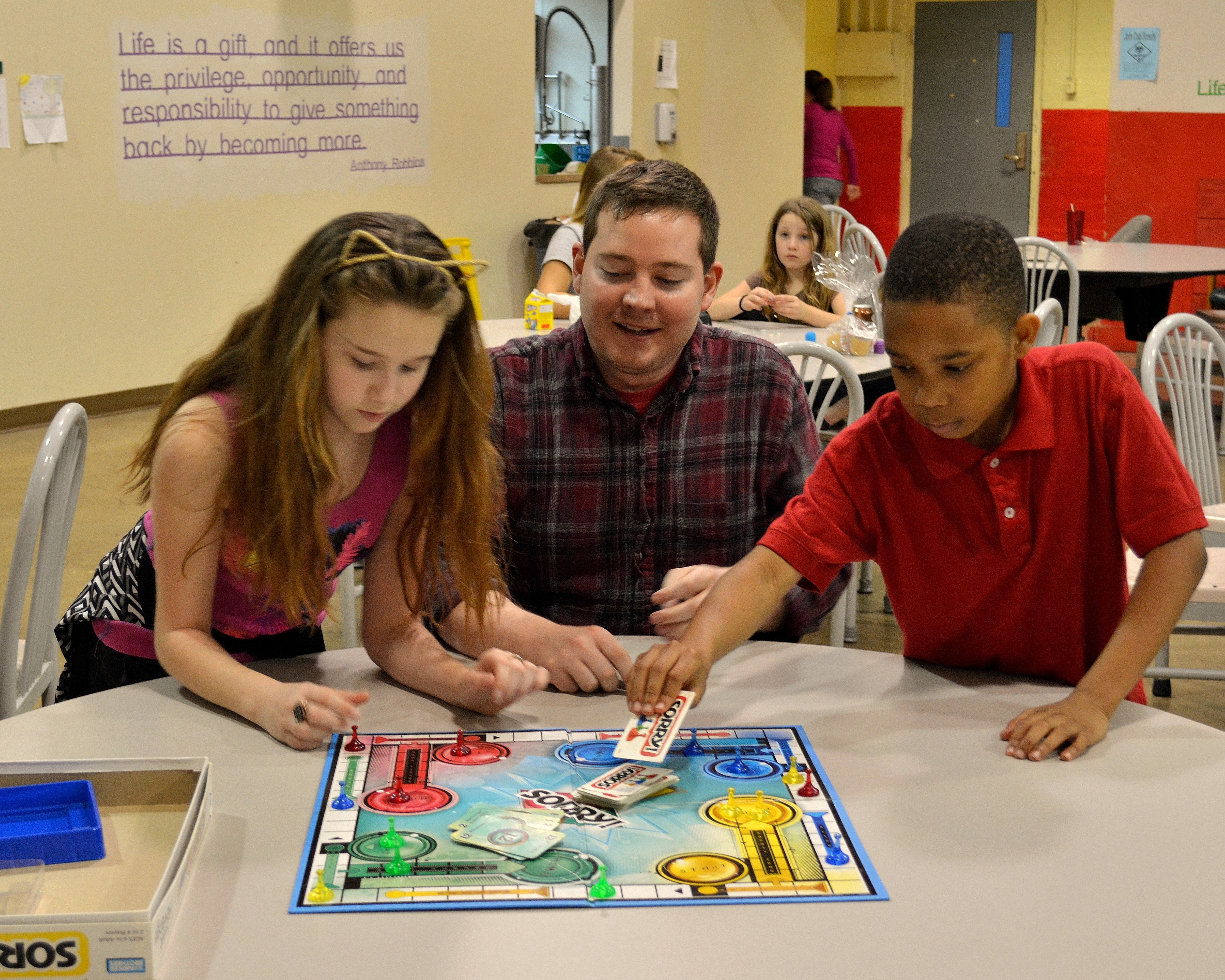 An adult and two children playing a board game at the Ryves Youth Center